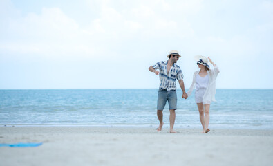 Young couple on vacation on a white sandy beach, clear sky and sea