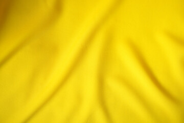 Close-up of yellow satin fabric in beautiful and luxurious waves.