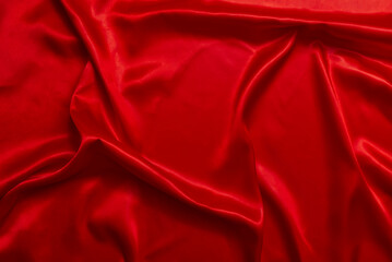 Close-up of red satin fabric in beautiful and luxurious waves.