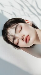 Obraz premium A woman with her head tilted to the side and her eyes closed. She is resting her head on her hand