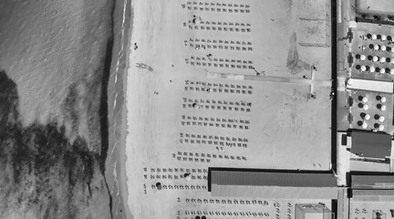 Aerial top-down view of a seaside beach resort with rows of umbrellas and sunbeds in summer