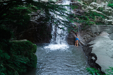 Beautiful girl bathing in a waterfall in the jungle