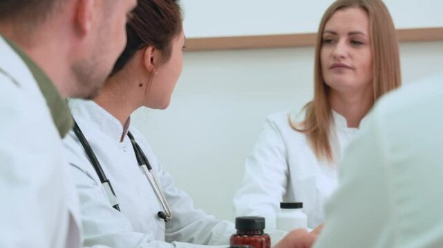 Medical professionals engage in a collaborative discussion, reviewing case files and strategies. Focus on team dynamics and shared decision-making in healthcare settings