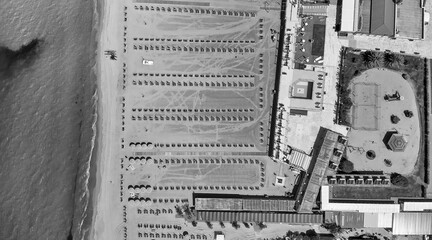 Drone shot of a vibrant beach club with rows of umbrellas and clear blue sea in the background