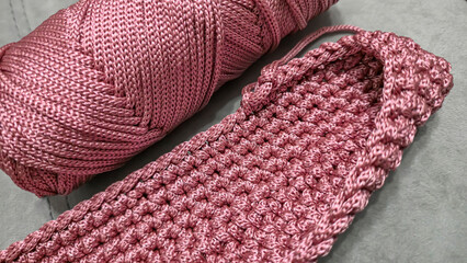 Knitting elements of a pink women's bag, hand knitting with a long handle.