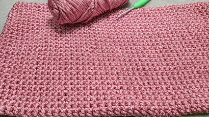 Knitting elements of a pink women's bag, hand knitting with a long handle.