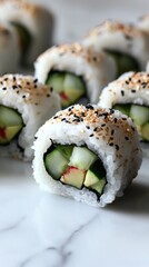 Close-up of fresh sushi rolls filled with avocado and cucumber, sprinkled with sesame seeds.