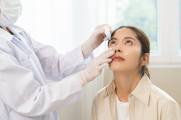 Health care concept, eye doctor eye drops to asian young woman patient, hand using medical eye drop...