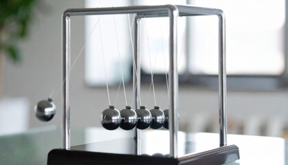 Newton's cradle in motion symbolizing physics, momentum, workplace decor and the concept of cause and effect in business and science