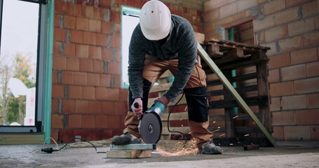 Worker using angle grinder, sparks flying from metal cutting, indoor construction site, focused on safety and precision, protective helmet and gear