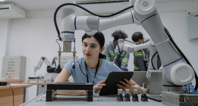Hispanic engineer woman working on AI technology in robotics electronics engineering laboratory. University students' research project is programming robot machine with intelligent mechanical control