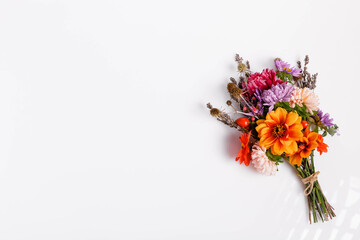 Autumn bouquet with pink yellow purple asters, orange dahlias, white background, minimal flatlay style, floral postcard design, celebration decor, top view, bright seasonal autumn composition