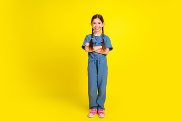 Cheerful young girl smiling in a stylish blue jumpsuit against a vibrant yellow background showcasing fun and confidence