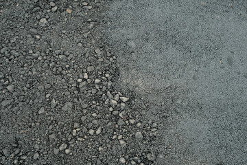 A black and gray road with a lot of rocks and gravel