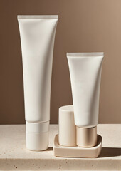 Minimalist blank white cosmetic tubes with gold bands set on neutral background