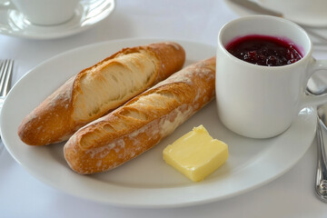 Typical French breakfast with a freshly baked baguette, butter, jam, and a cup of café au lait