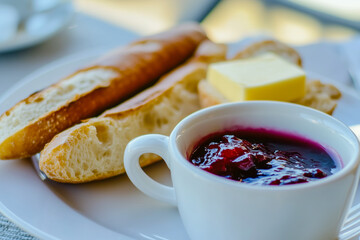Typical French breakfast with a freshly baked baguette, butter, jam, and a cup of café au lait