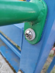 Close-up of Green and Blue Metal Structure with Shiny Hex Bolt and Minor Debris