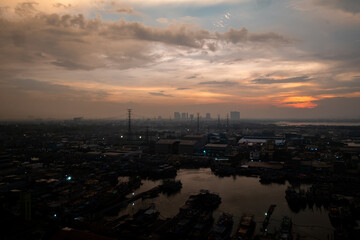 Fototapeta premium A vibrant sunset over Jakarta, with warm orange and red hues reflecting on the water, creating a dramatic and serene atmosphere.