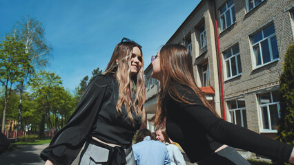 Fototapeta premium Two high school friends sharing a sweet kiss on the cheek to celebrate their affection and friendship