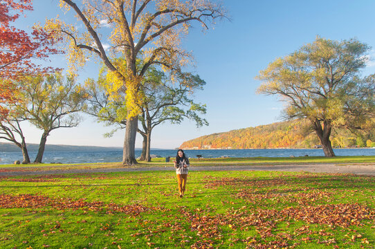 An asian woman walking through clute park on lake Seneca in Autumn