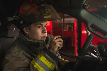 Firefighter driving a truck and talking on the radio to respond to a fire.