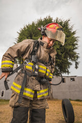 Fototapeta premium Brave firefighter putting on his air tank gear and other equipment to go fight a fire.
