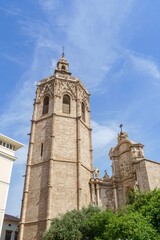 Micalet bell tower of Valencia Cathedral stands tall against a bright blue sky, showcasing its intricate historic architecture. This iconic landmark (Miguelete) is a must-see for tourists