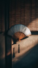 Elegant fan casts delicate shadows in a serene Japanese-inspired room at dusk
