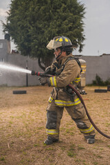 Brave firefighter behind a curtain of water standing in an epic pose putting out a fire.