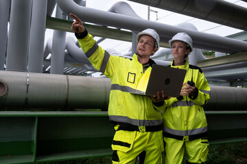 Workers assess pipeline infrastructure and discuss project details in a safety zone during daylight hours