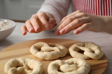 Woman with uncooked pretzels at table in kitchen, closeup