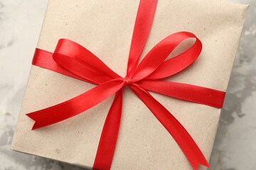 Gift wrapped in kraft paper with bow on grey textured background, closeup
