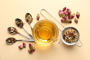 Delicious herbal tea in glass cup and dry leaves on beige background, flat lay