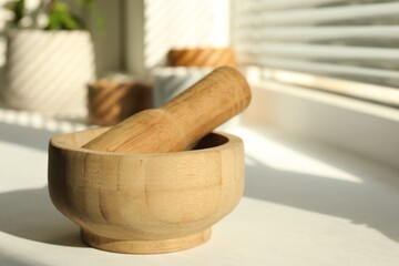 Wooden mortar and pestle on windowsill indoors, closeup. Space for text