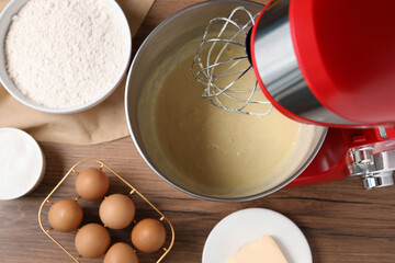 Stand mixer with dough and ingredients on wooden table, flat lay