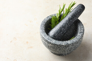 Stone mortar with rosemary and pestle on light table, closeup. Space for text