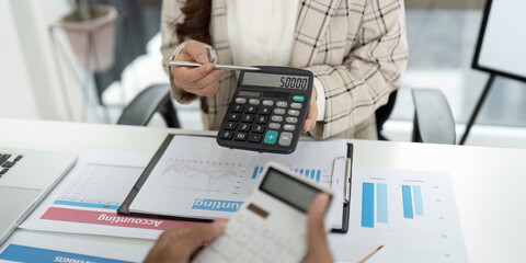 Financial Reporting. Accountant showing calculator display with figures during client meeting.