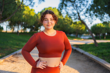 Plus size woman wearing sportswear posing in a park, promoting body positivity and self acceptance