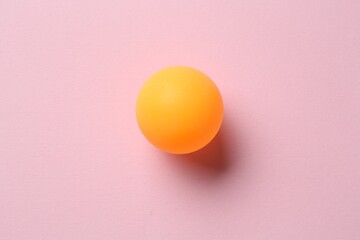 One ping pong ball on pink background, top view