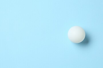 Ping pong ball on light blue background, top view. Space for text