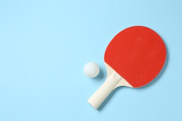 Ping pong racket and ball on light blue background, flat lay. Space for text