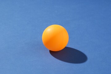 One ping pong ball on blue background, closeup
