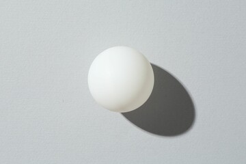 One ping pong ball on light background, top view