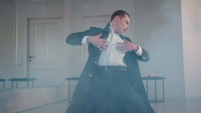 melodramatic dancer lies on ground enveloped in swirling smoke across studio floor, capturing intense emotional performance, fluid body movement, moody light, reflective mirror