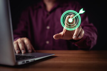 person in shirt uses a laptop while digitally pressing a glowing green target icon with an arrow,...