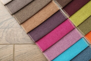 Samples of different fabrics on wooden table, top view