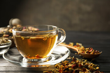 Refreshing herbal tea and dry leaves on black wooden table, closeup. Space for text