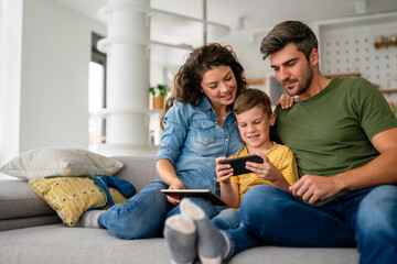 Happy family and kid having fun with smartphone, digital gadget at home. People, technology