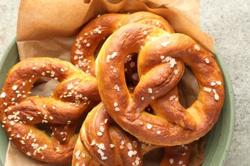 Tasty pretzels with salt on grey table, top view
